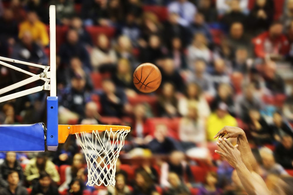 A basketball soars through the air towards the net.
