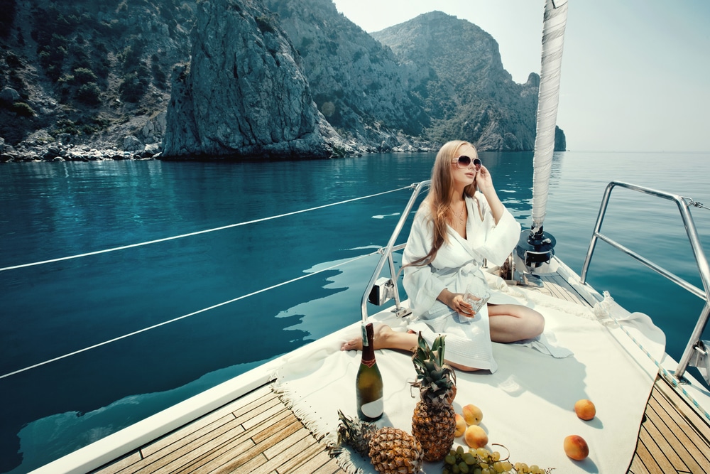 A young woman relaxing with wine and fresh fruit on the bow of a yacht.
