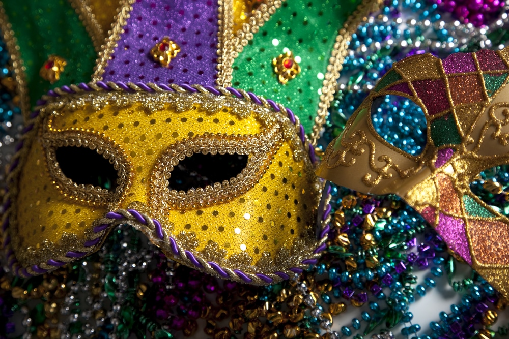 A close up of Mardi Gras beads and a mask.