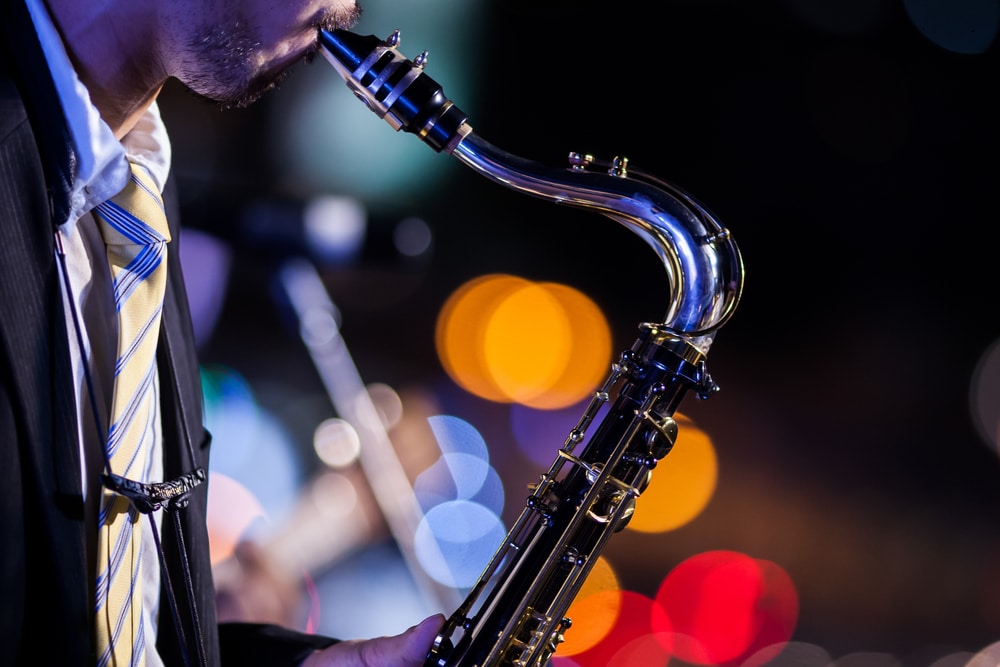 A jazz musician plays the saxophone against a backdrop of glowing lights.
