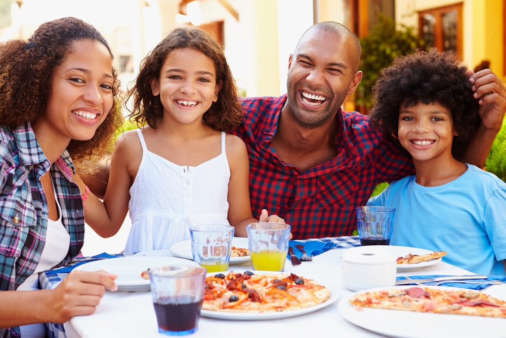 A portrait of a happy family eating pizza and laughing.