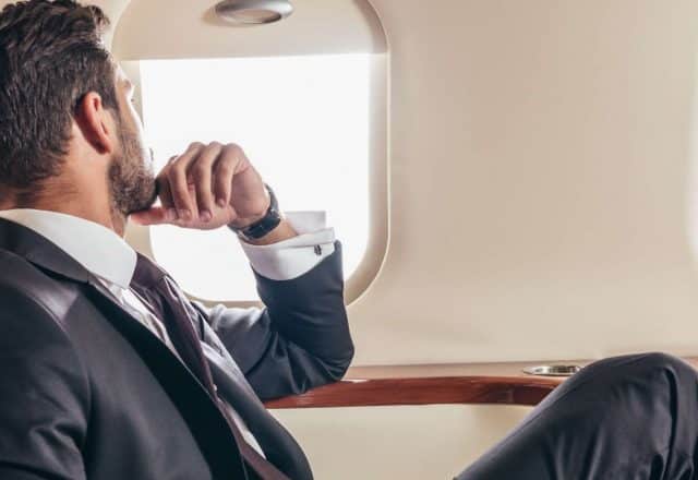 man looking out window of private jet