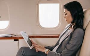 woman seated on private jet holding tablet