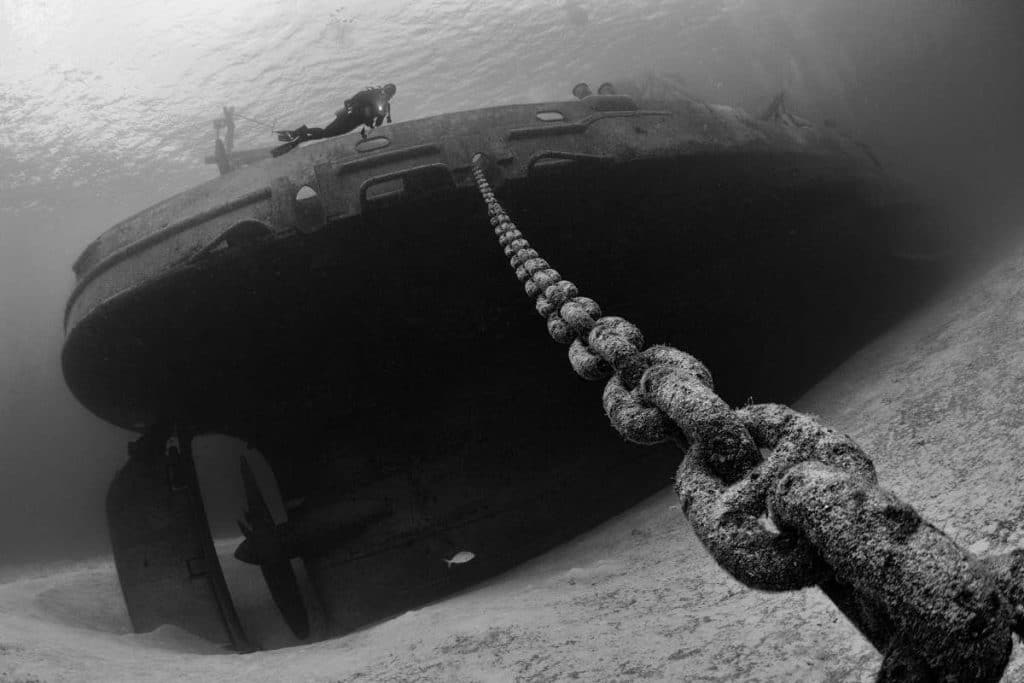 under water view of a ship wreck and large chain on sea floor