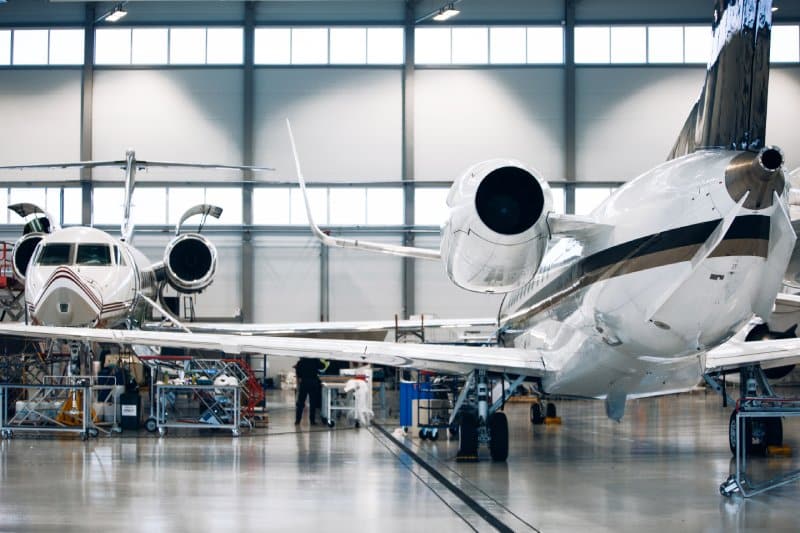 Two private jets under maintenance in a hangar.