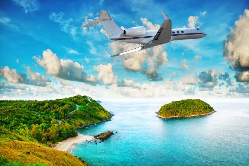 A private jet flying over an island in the Caribbean.