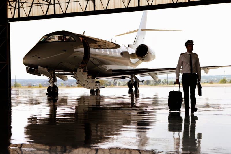 A private jet in a hangar as the pilot walks away.