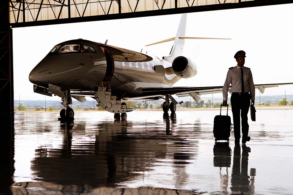 A private jet pilot walks away from a jet in a hangar