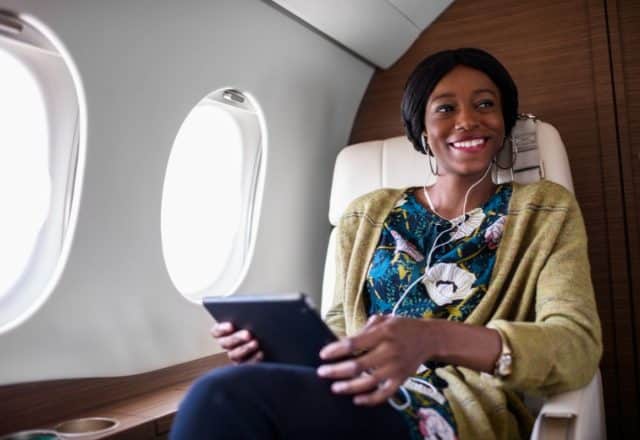 A woman uses her tablet to access private jet Wi-Fi
