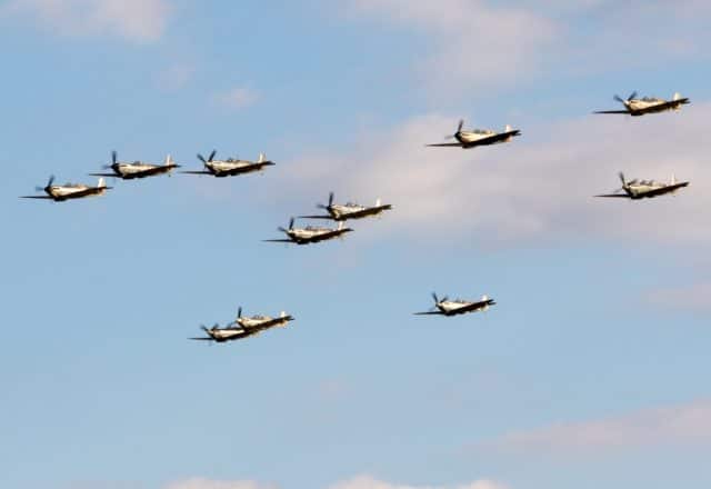 A group of Spitfire WW2 planes fly in formation.