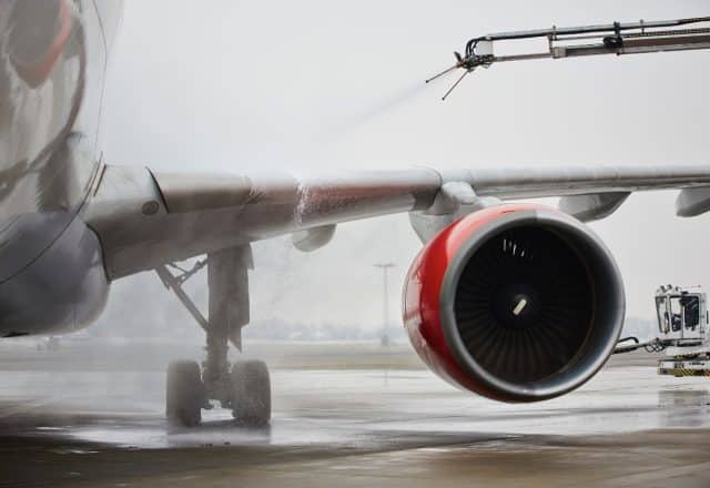 Aircraft de-icing crews spray the wings of a plane with de-icing fluids.