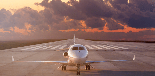 A private jet sits on a runway at sunset