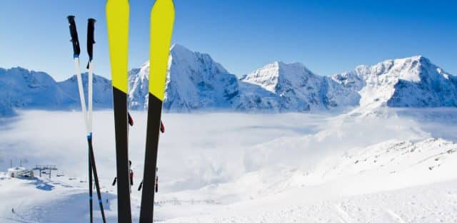 Skis in the snow below mountains