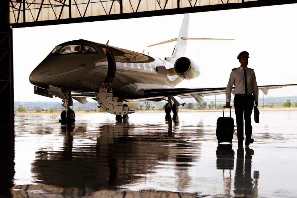 Silhouette of pilot walking away from private jet in hangar