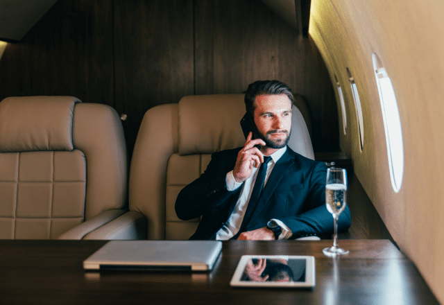 A man talks on a cellphone while sitting in a private jet