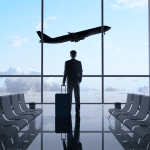 A business man stands with a suitcase at an FBO