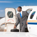 A man exits a private jet holding a briefcase