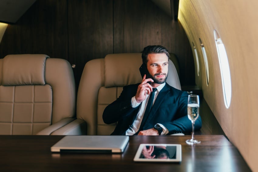 A businessman sitting on a private plane talking on the phone