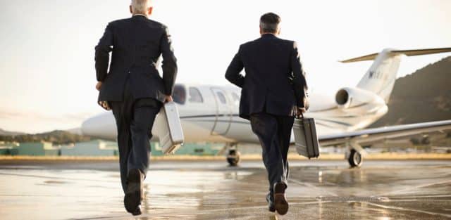 Two people in suits walk towards an on-demand jet charter