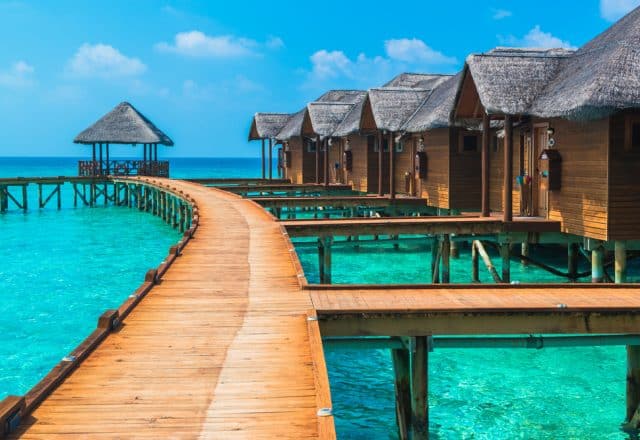 Overwater bungalows reach far into the horizon, appearing to float atop crystal blue waters in the Maldives.