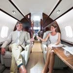 A happy couple toasts champagne while sitting in their private jet.