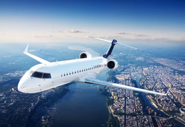 A private jet soars above a modern city.
