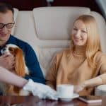 A couple with a dog sit on a private jet flight.