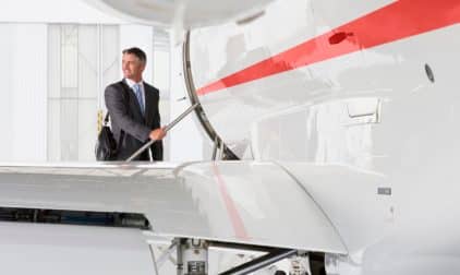 A businessman looks over his shoulder as he boards a private jet.