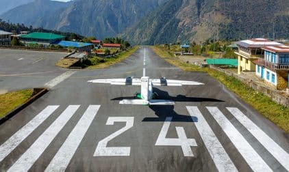 An aircraft on the runway overlooking a steep drop off in the mountains.