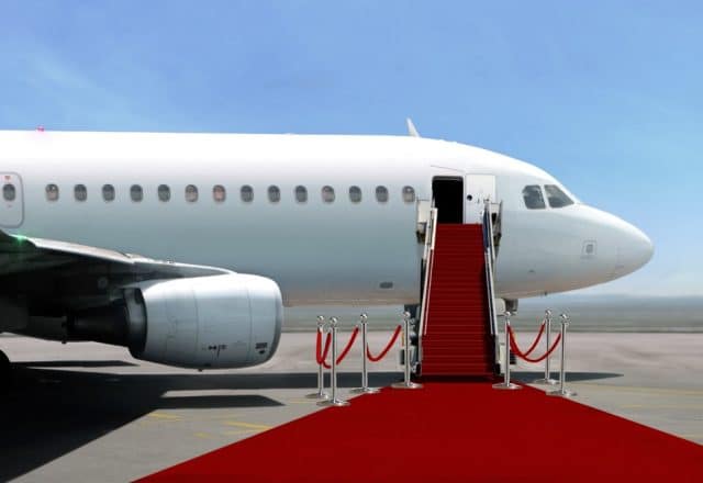 An airplane on the ground with a red carpet