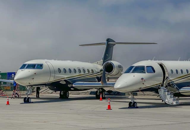 Two private jets sit on a runway.