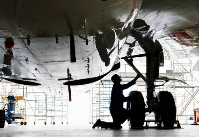 An engineer inspecting the landing gear of a passenger jet in a hangar