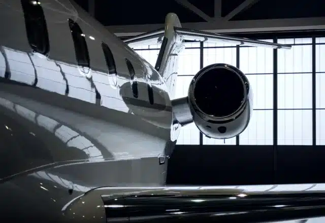 A jet sits inside an FBO hangar at an airport