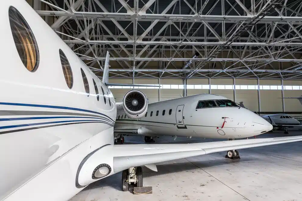 Four private jets in a large hangar.